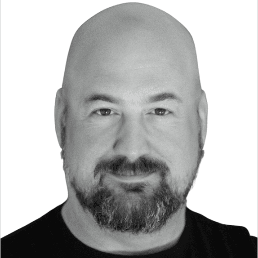 A sharp-eyed male executive in his 40s, dressed in business casual, against a dark steel-textured background.