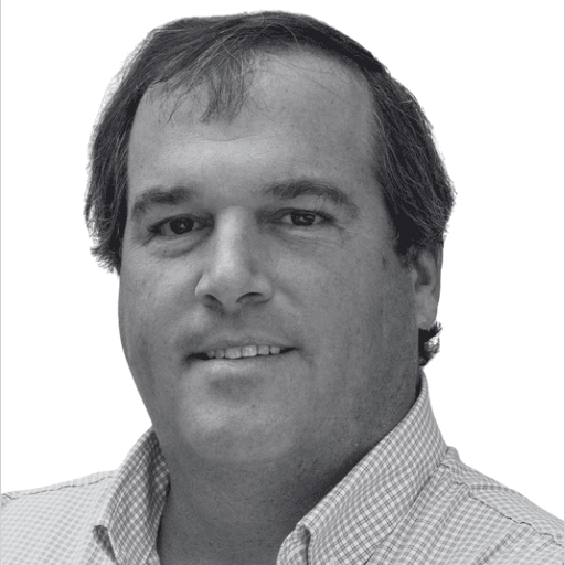 A senior male executive in his 50s with a confident, approachable expression. High-contrast black and white portrait.